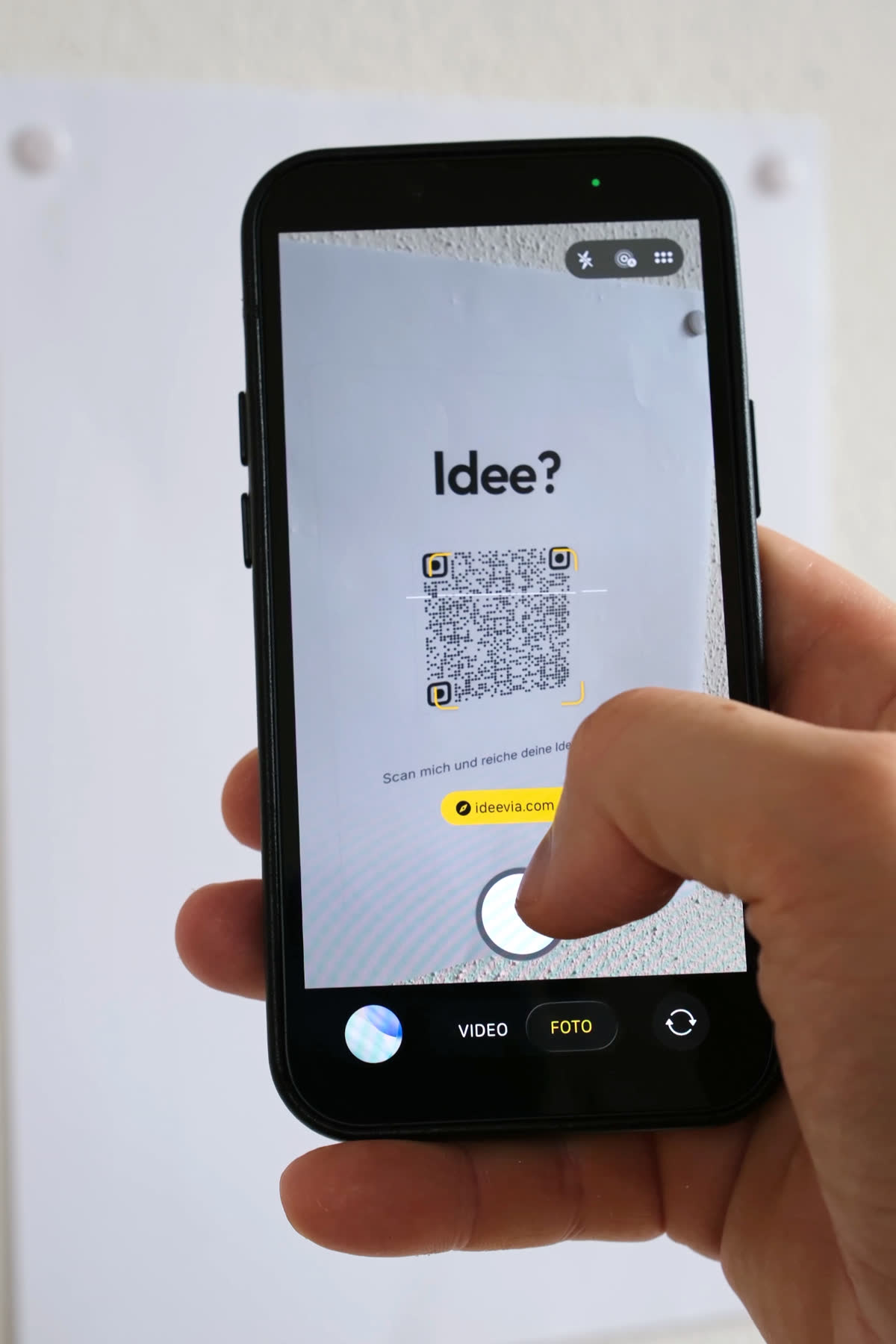 Mitarbeiter scannt den Idee?-Aushang mit dem Handy